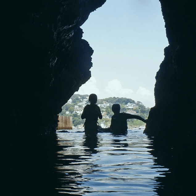 Guided coasteering group in a sea cave on the Salcombe coastline, South Devon